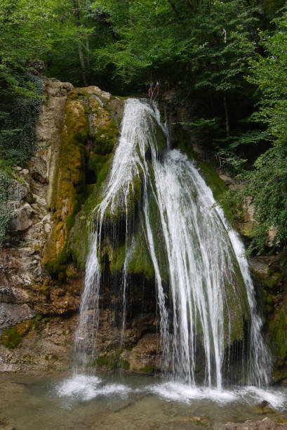 istock A small waterfall. White from foam water flows down the green of moss stones 1003403060