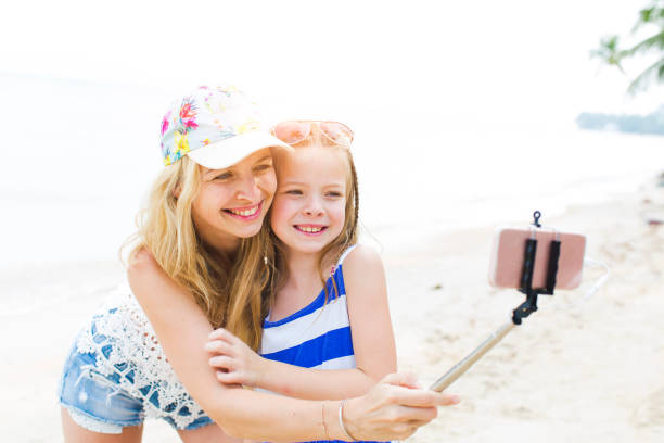 istock Cheerful Mother And Daughter Taking Selfie At Beach 1003403156