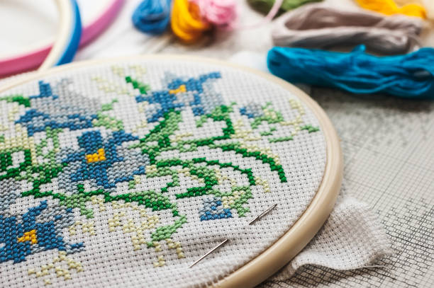 배경에 화려한 원사로 흰색 직물에 바느질 패턴을 닫습니다 - cross stitch 뉴스 사진 이미지