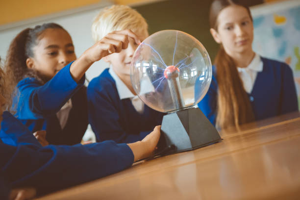 Group of student touching plasma ball during physics lesson at school.
