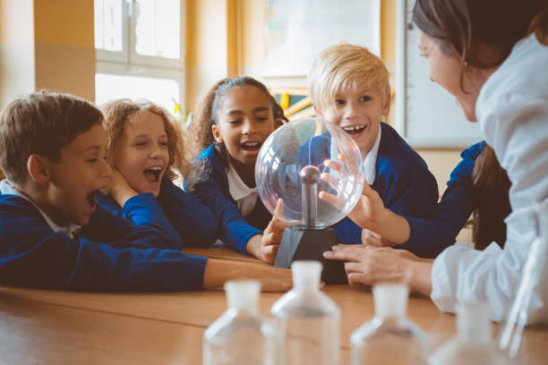 female teacher showing plasma ball during lesson at school - physics classroom teaching professor imagens e fotografias de stock