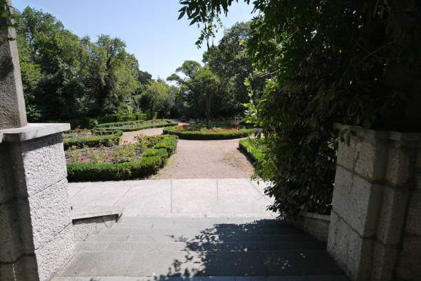 istock Stone steps leading to a small decorative square with a round flower bed in the middle 1003420554