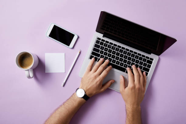 istock cropped shot of man using laptop at workplace on pink surface for mockup 1003422920