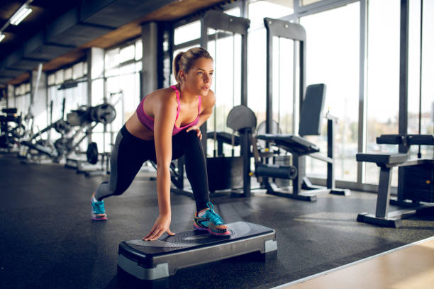 istock Woman doing lunges on step aerobics equipment at gym 1003426108