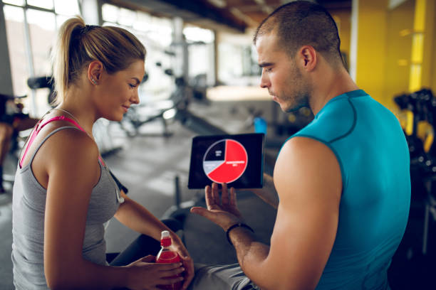istock Trainer explaining workout regime to young sporty woman 1003430810