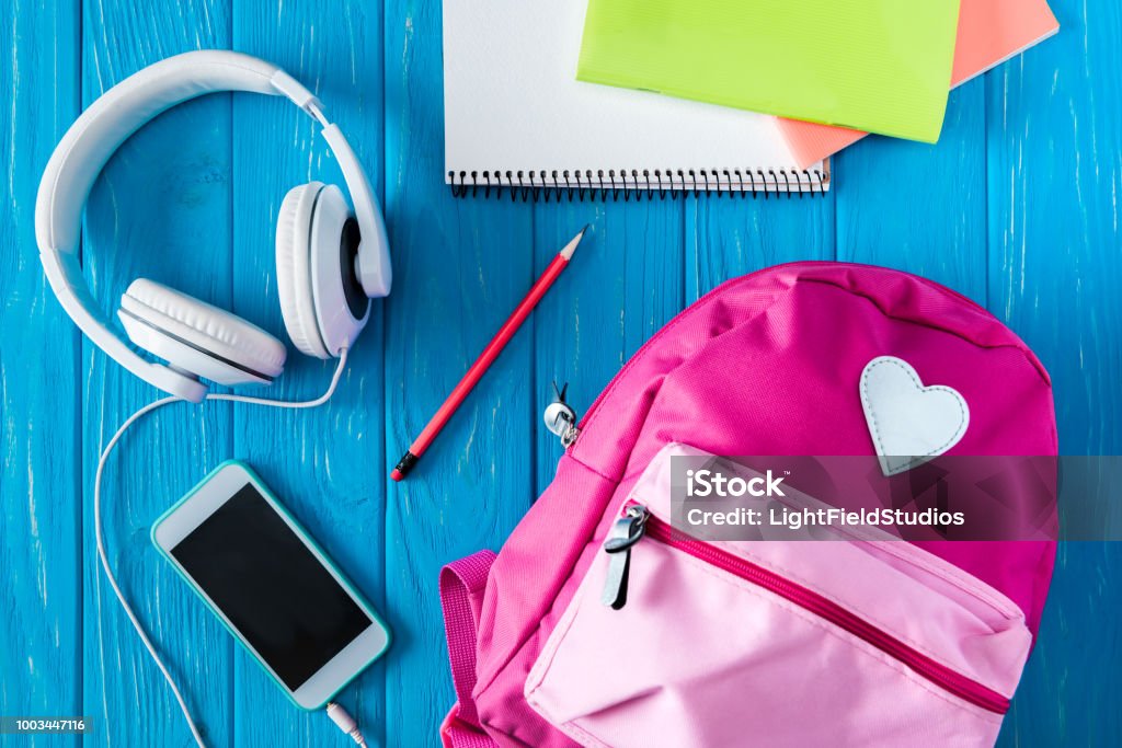 Vista Superior De La Mochila Rosa Smartphone Con Pantalla En Blanco Los Auriculares Y Los Libros De Texto Sobre Fondo De Madera Azul Foto de stock y más banco de imágenes de Vista Superior De La Mochila Rosa Smartphone Con Pantalla En Blanco Los Auriculares Y Los Libros De Texto Sobre Fondo De Madera Azul Foto de stock y más banco de imágenes de