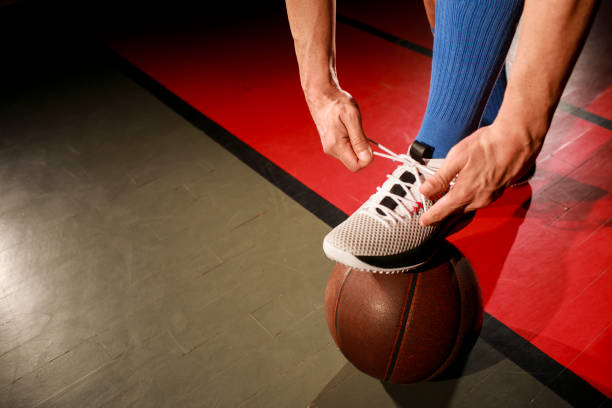 istock Basketball player tying shoelaces while standing on basketball. 1003449308