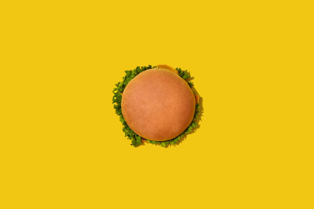 gustoso hamburger fresco malsano con ketchup e verdure su sfondo giallo vibrante e luminoso. visualizzazione superiore con spazio di copia - burger bun sandwich bread foto e immagini stock