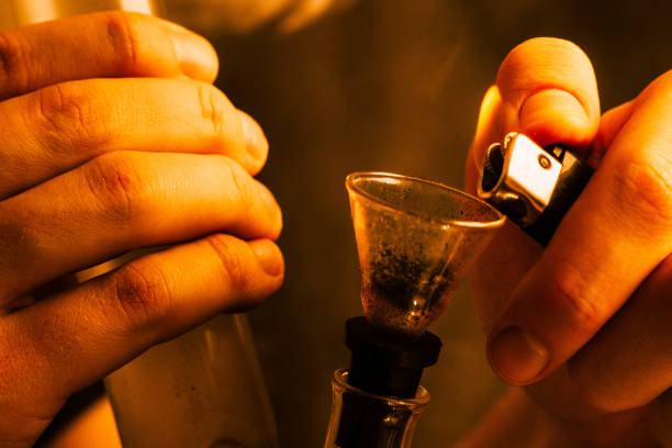 istock A man smokes cannabis weed, a joint and a lighter in his hands. Yellow toning 1003458318
