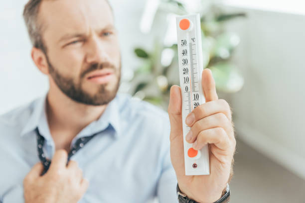 istock selective focus of businessman in hot office looking at thermometer 1003474522