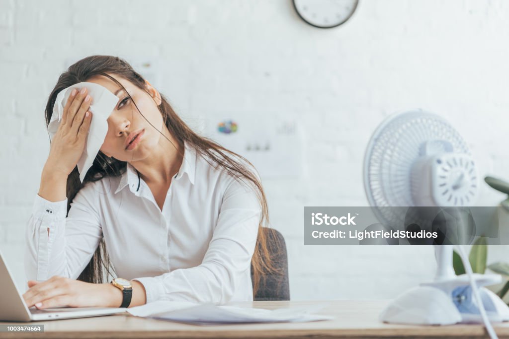 empresaria sudorosa trabajando en oficina con ventilador eléctrico - Foto de stock de Sudor libre de derechos