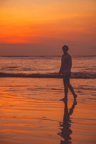istock Man enjoying on the ocean beach in sunset / sunrise time. 1003475448