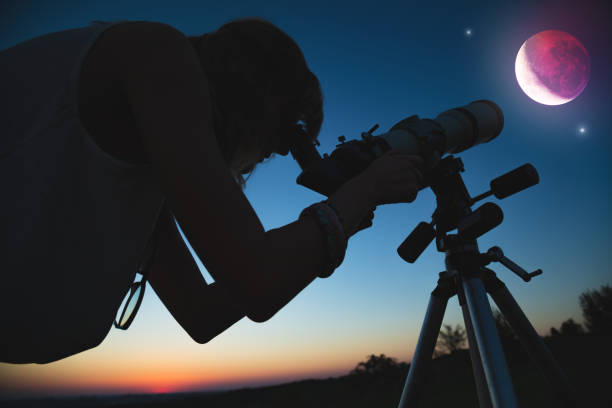 istock Girl looking at lunar eclipse through a telescope. My astronomy work. 1003476928