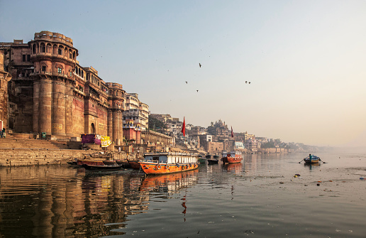 Life along the Ganges (Ganga) River.Pilgrims bath and pray, people walk,washes and dry laundry.Tourists take boat to sea old temples and ghats from the river