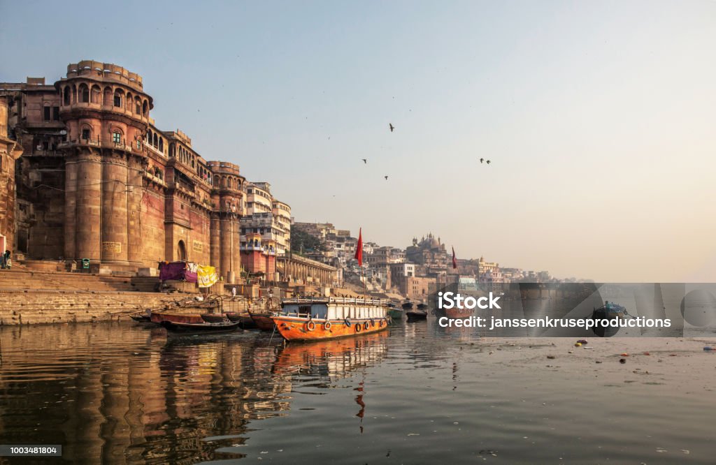 Life along the Ganges (Ganga) River.Pilgrims bath and pray, people walk,washes and dry laundry.Tourists take boat to sea old temples and ghats from the river Varanasi Stock Photo