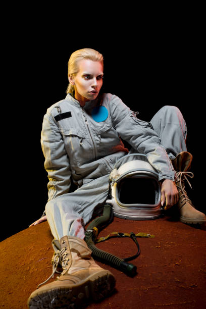 istock attractive cosmonaut in spacesuit holding helmet sitting on planet 1003485380