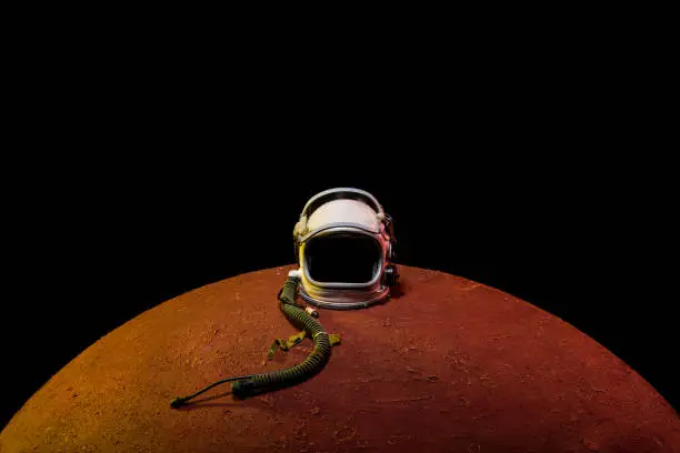 helmet from spacesuit lying on mars planet in black universe
