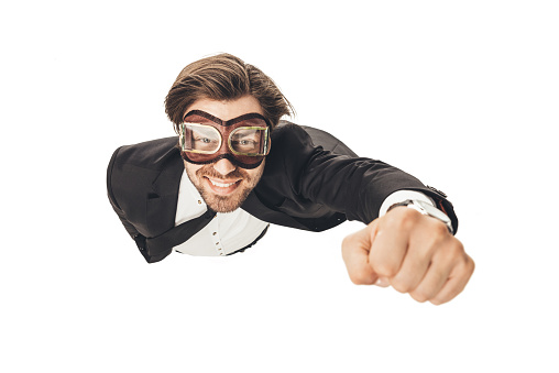 handsome young businessman in vintage aviation goggles flying like superhero isolated on white