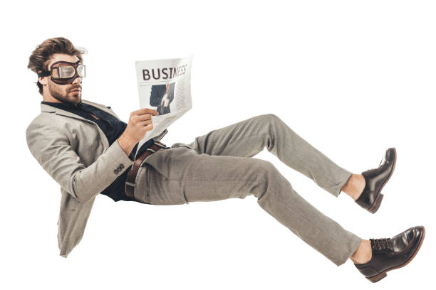 istock handsome young businessman in vintage aviation goggles reading newspaper while falling isolated on white 1003490552