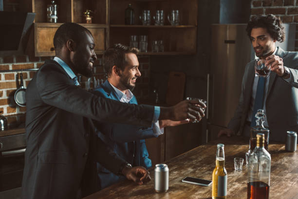 istock happy multiethnic men drinking whisky and partying together 1003529510