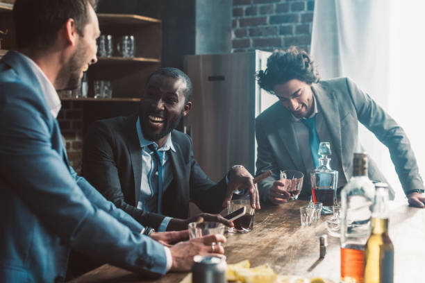 istock cheerful male friends laughing and drinking whiskey together 1003529548