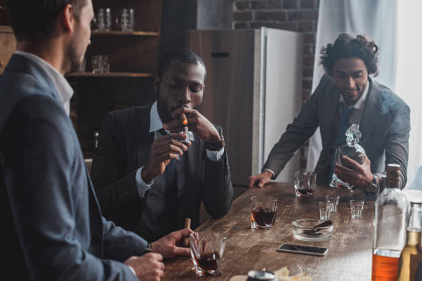 istock three multiethnic men in suits smoking cigars and drinking alcohol together 1003529550