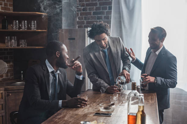 istock male friends talking while drinking alcohol and smoking cigars 1003529582