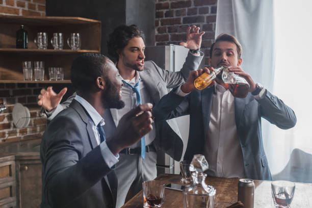 istock excited multiethnic men looking at friend drinking alcoholic beverages from bottles 1003529660