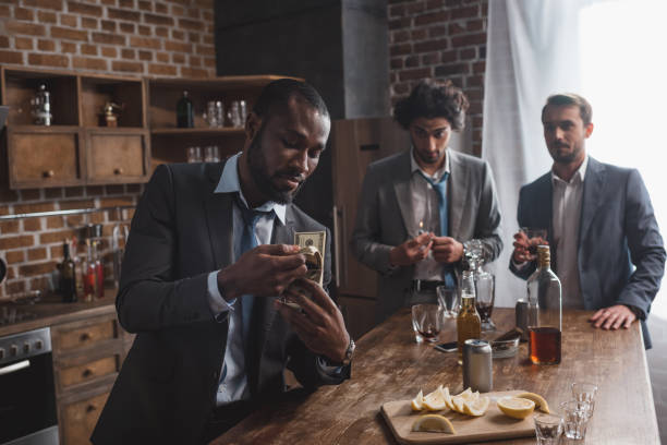 istock african american businessman counting dollar banknotes while drinking alcohol with friends 1003529682