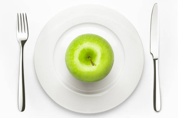 istock Diet concept, green apple on a white plate, fork, knife, weight 1003529742