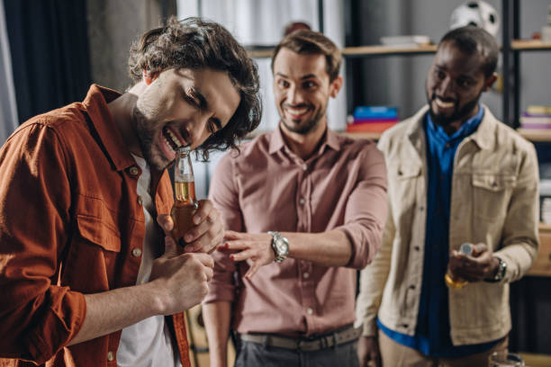 sorrindo multiétnicas homens olhando amigo abrir a garrafa de cerveja com os dentes - stag night fotos - fotografias e filmes do acervo