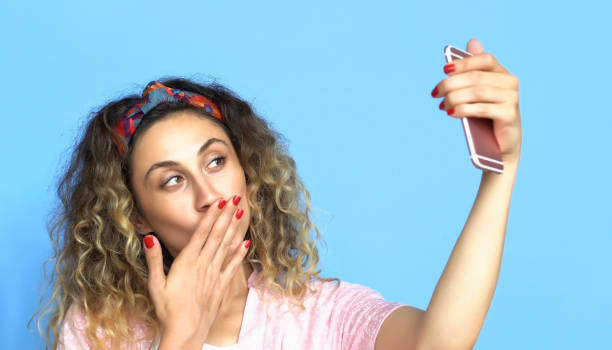 istock Woman is using Mobile Phone - Selfie - Blue background 1003545670
