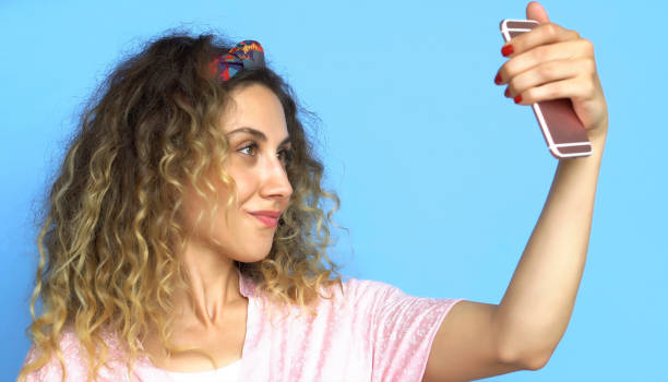istock Woman is using Mobile Phone - Selfie - Blue background 1003545872