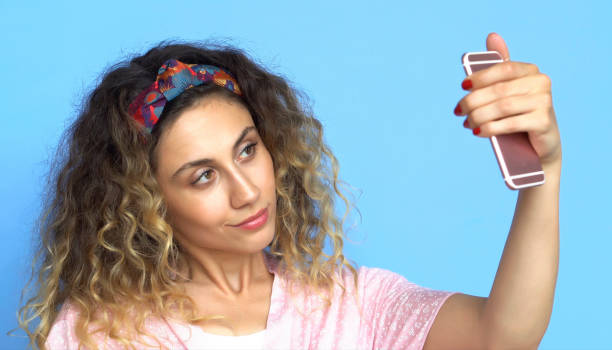 istock Woman is using Mobile Phone - Selfie - Blue background 1003545976