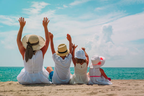 istock happy mother with kids hands up on the beach 1003546370