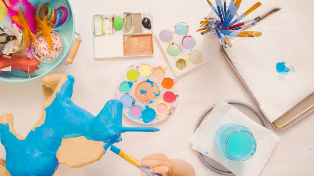 istock Painting paper mache unicorn with blue paint. 1003550952