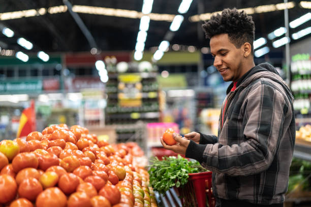 cliente che sceglie pomodori al supermercato - supermarket shopping retail choice foto e immagini stock