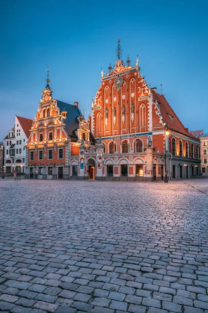 Photo of Riga, Latvia. Schwabe House And House Of The Blackheads At Town Hall Square, Ancient Historical Landmark And Popular Touristic Showplace In Summer Evening Or Night