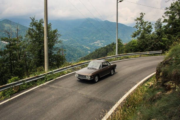 istock Classic car turning in front of beautiful hills and sky 1003561306