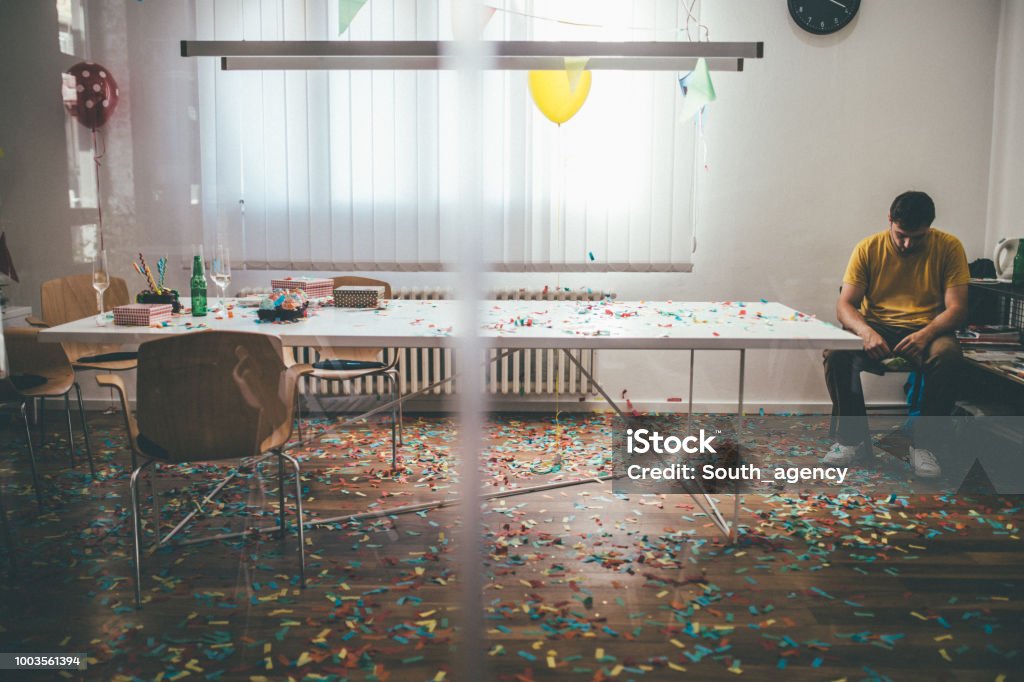 Messy office Tired man cleaning messy office after party Party - Social Event Stock Photo