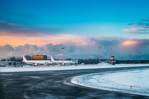 Aircraft stand on ground at International Airport terminal in early morning with beautiful sunrise dramatic sky.