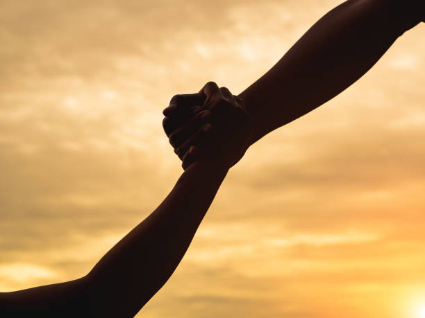 istock Closeup helping hands on the sunset sky background. Rescue & Help Concept 1003566056