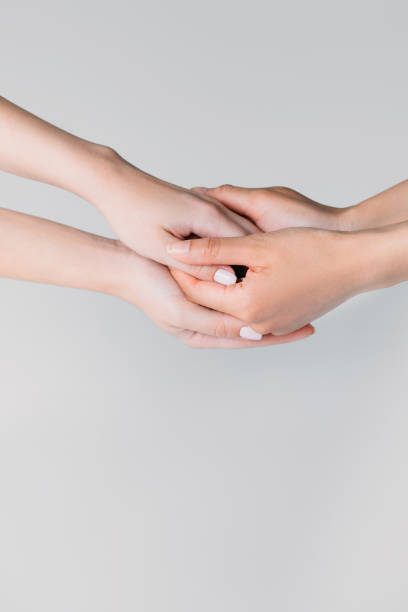 istock partial view of girls holding hands, isolated on grey 1003568518