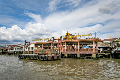 Bangkok, Thailand - May 02 2018:  The Chao Phraya river runs through the centre of Thailand’s capital city, Bangkok.  The express boat service is part of the cities major transport network, with multiple Piers along the route.  Here we see the Wat Devaraj Kunchorn Voraviharn, a temple built in the Ayuthaya period.