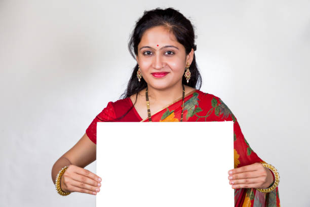 una joven india treintañera con un sari rojo que muestra una pizarra o un cartel contra un fondo blanco - businesswoman advertise placard advertisement fotografías e imágenes de stock