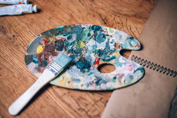 istock palette with oil paints and a brush on a wooden table. 1003584340