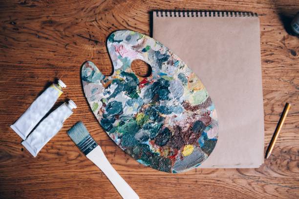 istock palette with oil paints and a brush on a wooden table. 1003584376