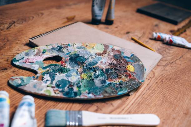 istock palette with oil paints and a brush on a wooden table. 1003584432