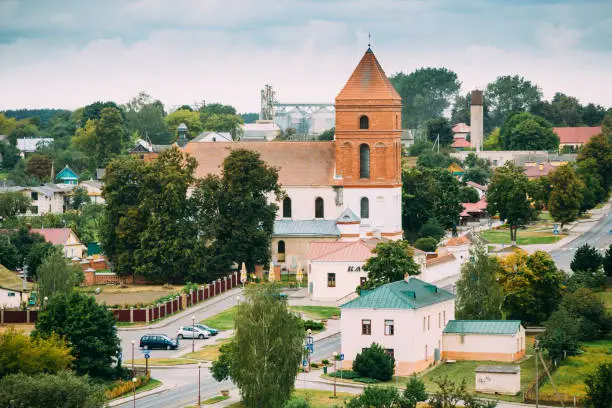 Photo of Mir, Belarus. Landscape Of Village Houses And Saint Nicolas Roman Catholic Church In Mir, Belarus. Famous Landmark