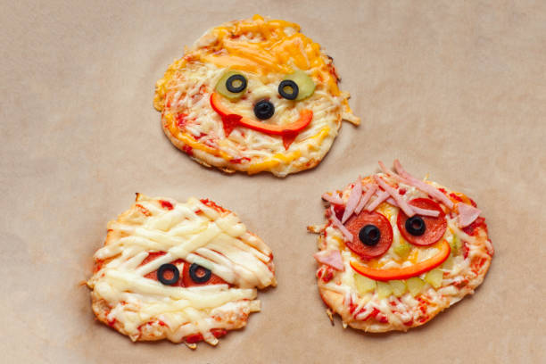 istock Halloween pizza with monsters, above scene with decor on a craft paper box background, idea for home party food, easy, healthy and delicious fun food party treats for kids 1003589486